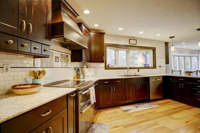 kitchen featuring stainless steel appliances, light wood-type flooring, light stone countertops, pendant lighting, and sink