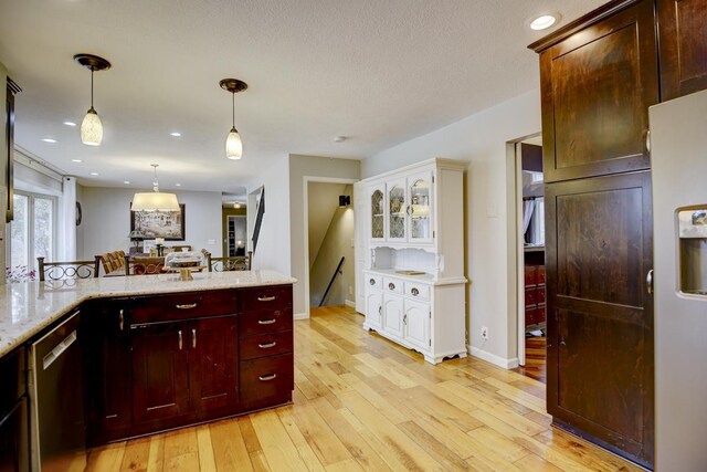 kitchen featuring light hardwood / wood-style floors, stainless steel dishwasher, light stone counters, and hanging light fixtures