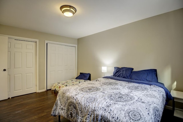 bedroom featuring multiple closets and dark wood-type flooring