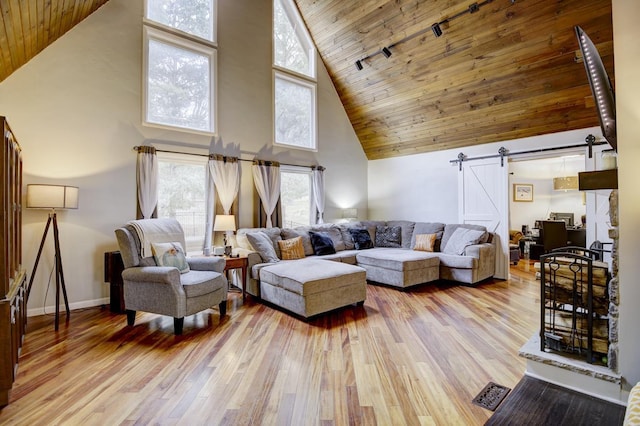 living room with wooden ceiling, light hardwood / wood-style floors, a barn door, and a high ceiling