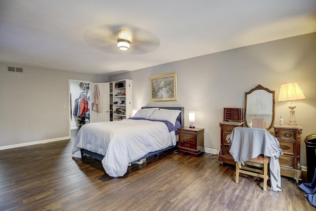 bedroom with ceiling fan, dark hardwood / wood-style flooring, a spacious closet, and a closet