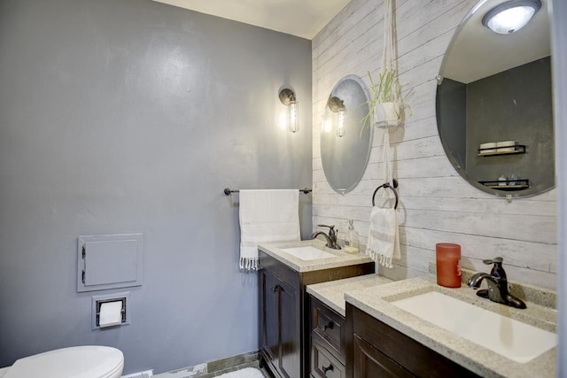 bathroom with vanity, toilet, and wooden walls