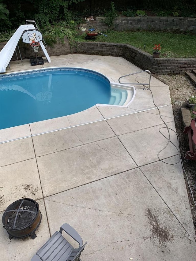 view of pool with an outdoor fire pit, a water slide, and a patio