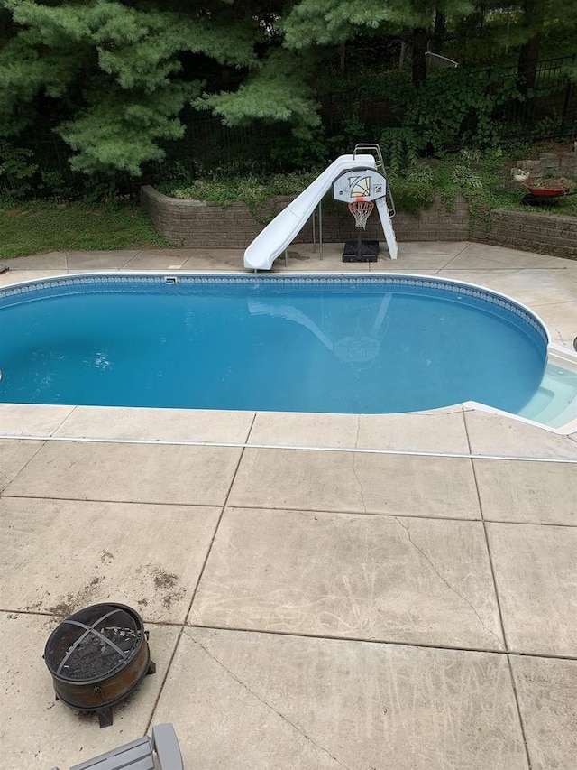 view of swimming pool with an outdoor fire pit and a water slide