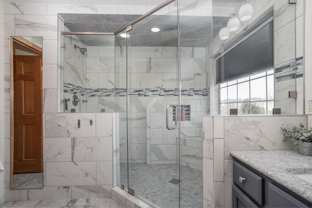 bathroom with a shower with shower door and vanity