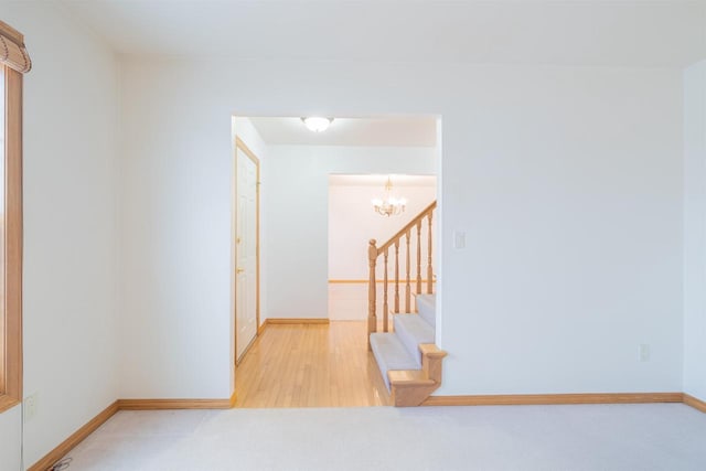 hall featuring light carpet and a notable chandelier