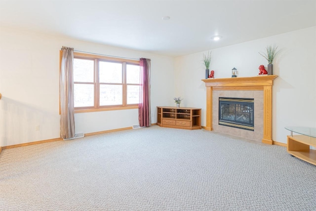 unfurnished living room featuring carpet floors and a tiled fireplace