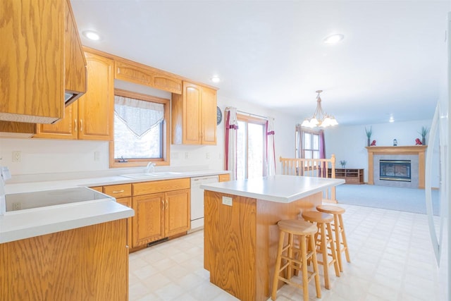 kitchen featuring pendant lighting, a kitchen island, sink, a kitchen breakfast bar, and white dishwasher