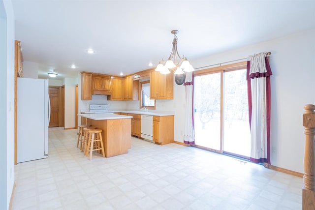 kitchen with white appliances, a center island, hanging light fixtures, a chandelier, and a breakfast bar area