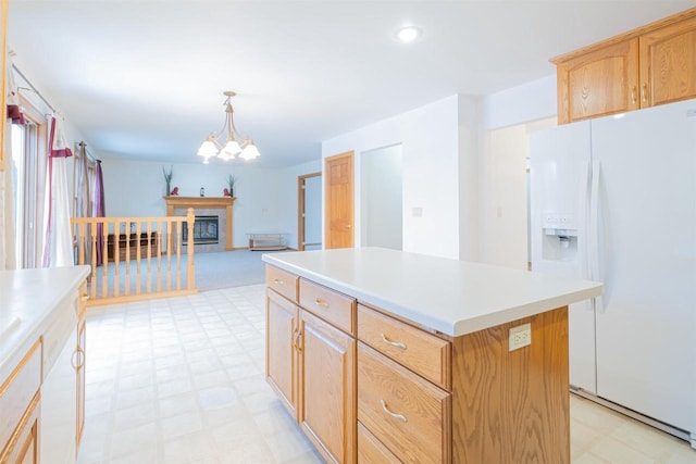 kitchen with a notable chandelier, pendant lighting, a center island, light brown cabinets, and white fridge with ice dispenser