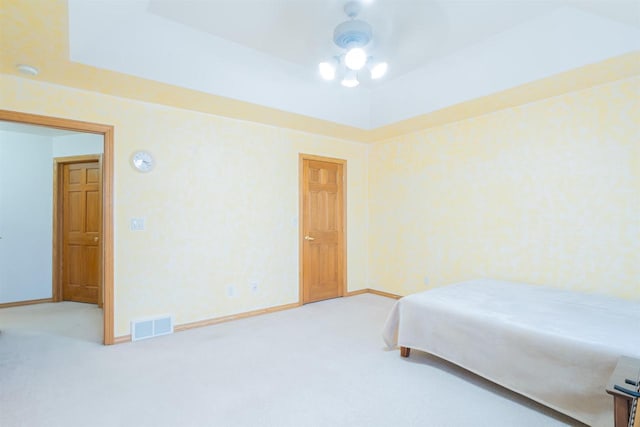 bedroom featuring ceiling fan, a raised ceiling, and carpet floors