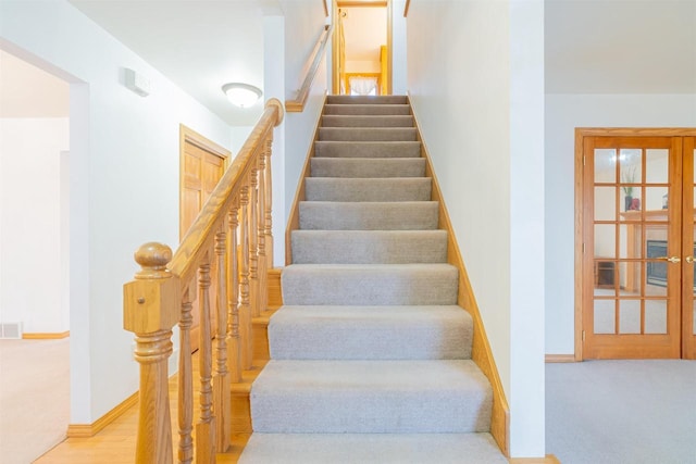 stairs featuring french doors and hardwood / wood-style floors