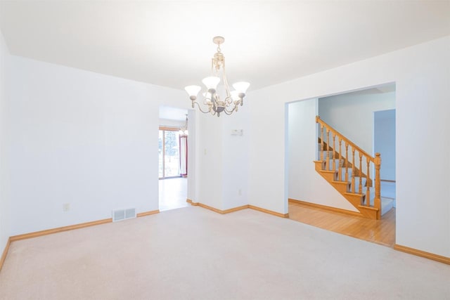 spare room with carpet floors and a notable chandelier