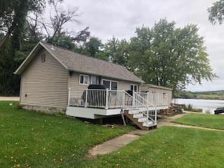 back of property with a lawn and a deck with water view