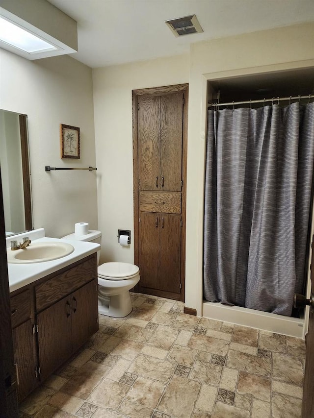 bathroom with toilet, walk in shower, and vanity