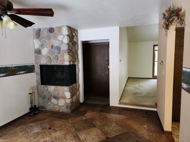 unfurnished living room featuring ceiling fan and a fireplace