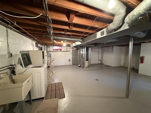 basement with water heater, heating unit, washing machine and clothes dryer, and sink