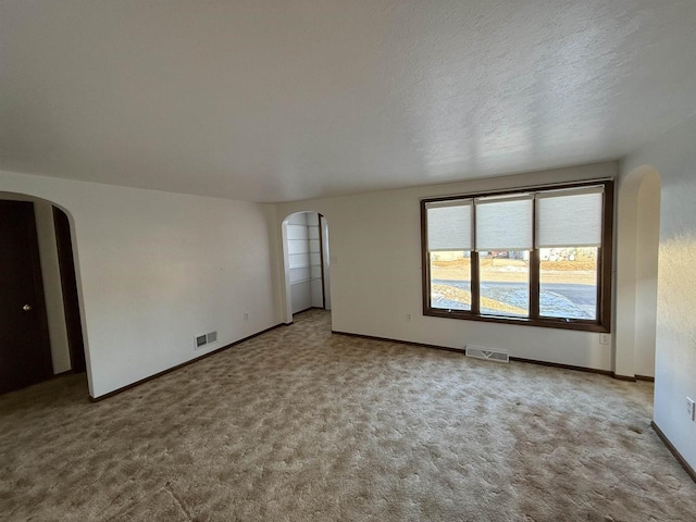 carpeted empty room featuring a textured ceiling