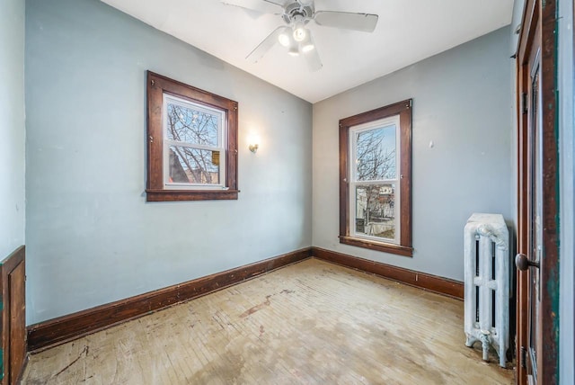 unfurnished room featuring ceiling fan, radiator, and light hardwood / wood-style flooring