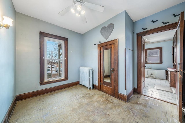 empty room featuring ceiling fan, light hardwood / wood-style floors, and radiator heating unit