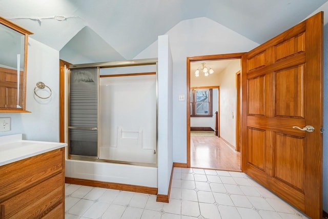 bathroom featuring combined bath / shower with glass door, vanity, vaulted ceiling, and an inviting chandelier