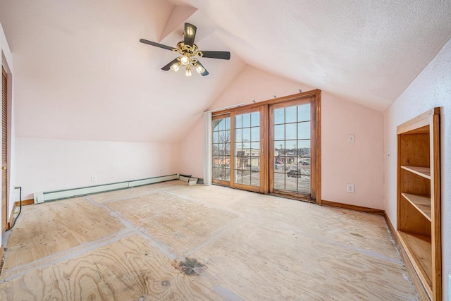 additional living space with ceiling fan, a baseboard heating unit, and vaulted ceiling