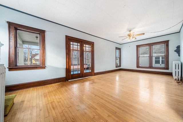 spare room featuring ceiling fan, light wood-type flooring, french doors, radiator, and crown molding