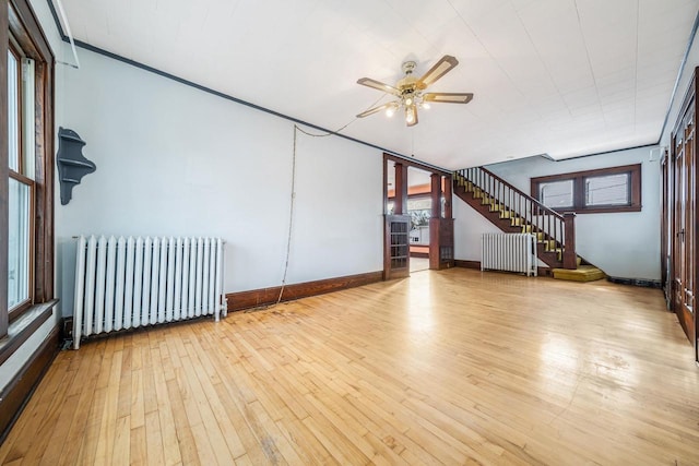 empty room with ceiling fan, light hardwood / wood-style floors, and radiator heating unit