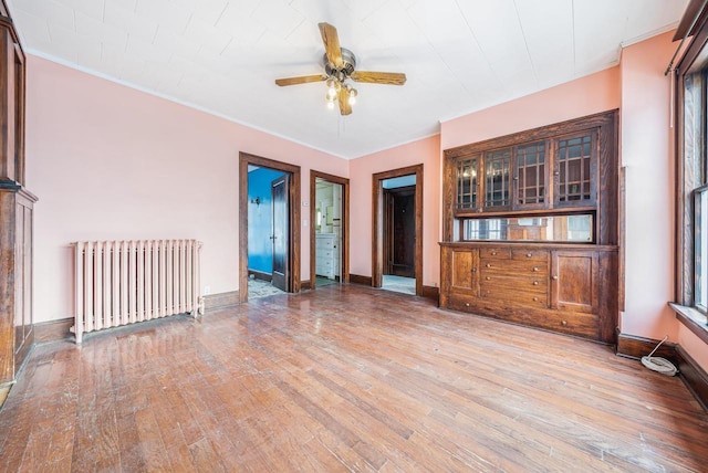 unfurnished living room with ceiling fan, crown molding, radiator heating unit, and hardwood / wood-style floors