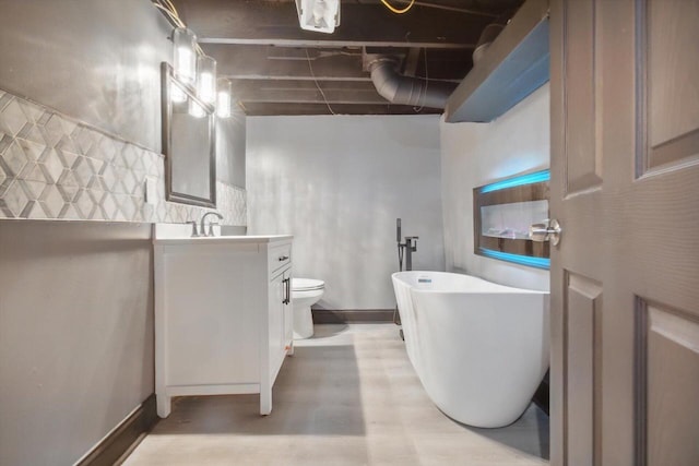 bathroom featuring toilet, vanity, and a bath