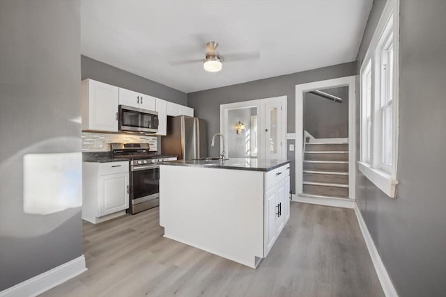 kitchen featuring stainless steel appliances, white cabinets, tasteful backsplash, and a kitchen island with sink