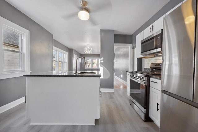 kitchen featuring a center island with sink, appliances with stainless steel finishes, white cabinetry, and sink