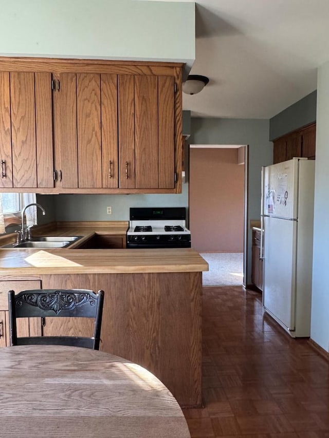 kitchen featuring dark parquet flooring, kitchen peninsula, sink, and white appliances