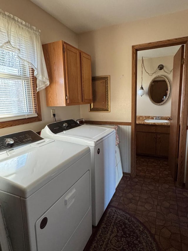 clothes washing area with washing machine and dryer, sink, and cabinets