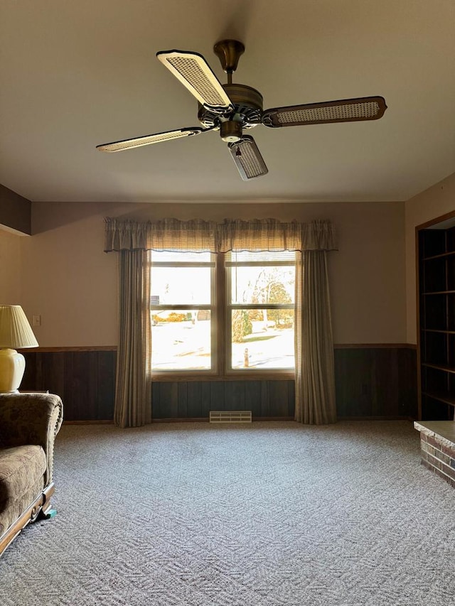 unfurnished room with ceiling fan, carpet flooring, and wooden walls