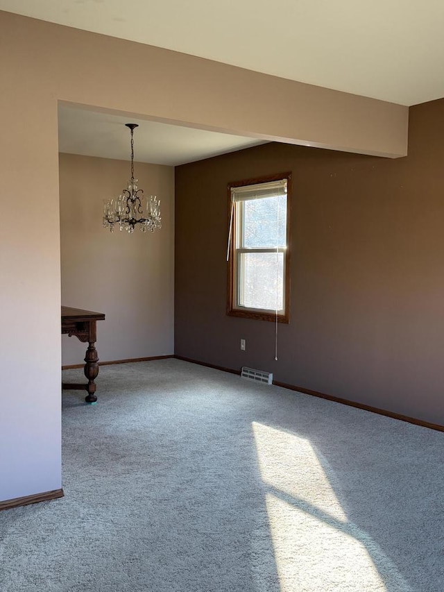 spare room featuring carpet and a notable chandelier