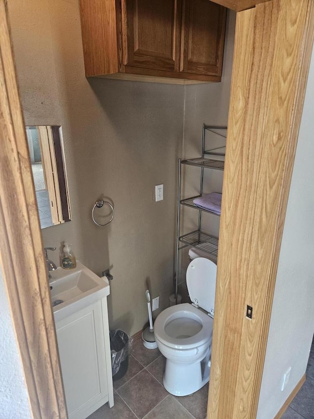 bathroom with toilet, vanity, and tile patterned flooring