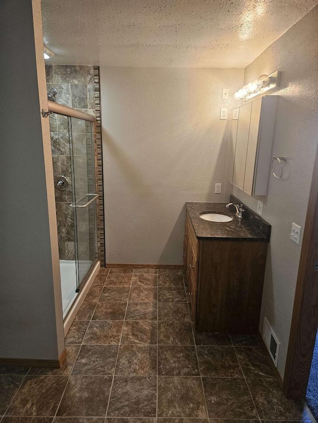 bathroom with a textured ceiling, an enclosed shower, and vanity