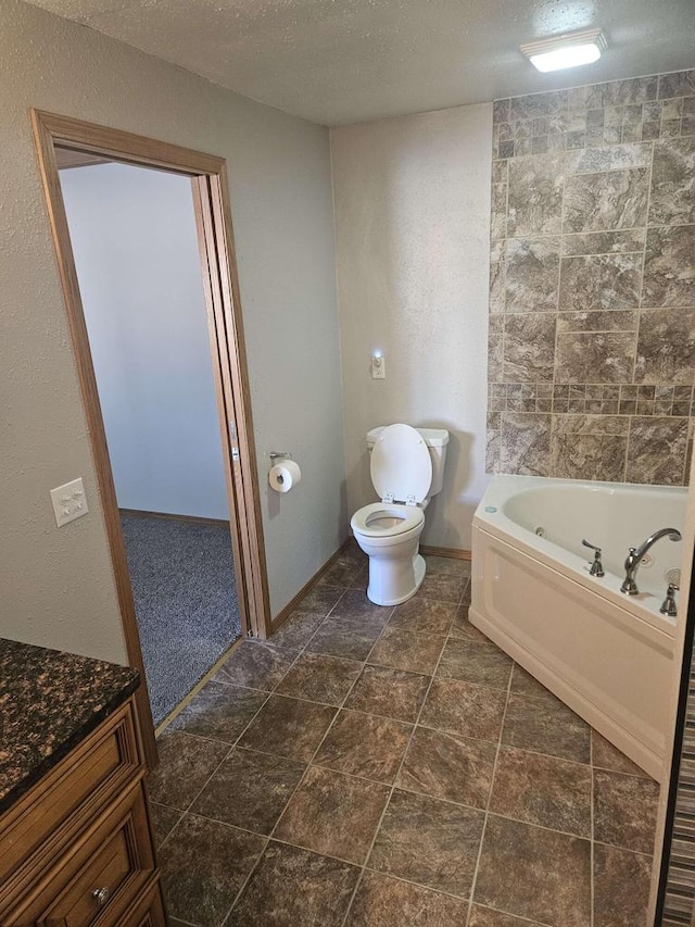 bathroom with a washtub, a textured ceiling, toilet, and vanity