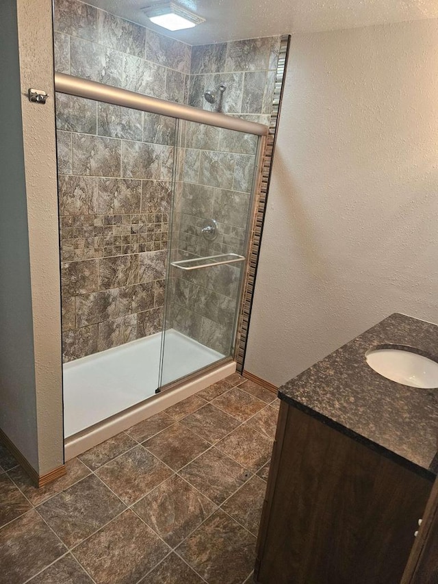 bathroom featuring a shower with door and vanity