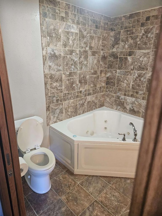 bathroom with a tub to relax in and toilet