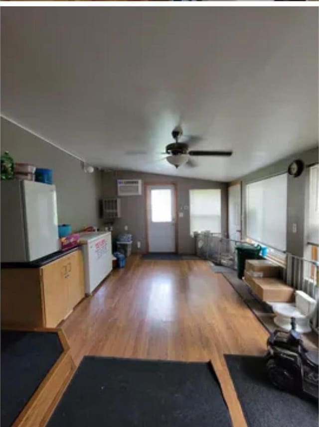 living room featuring ceiling fan, wood-type flooring, and a wall unit AC