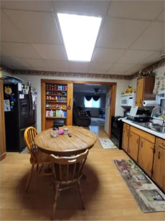 kitchen with sink, electric range, black fridge, and a drop ceiling