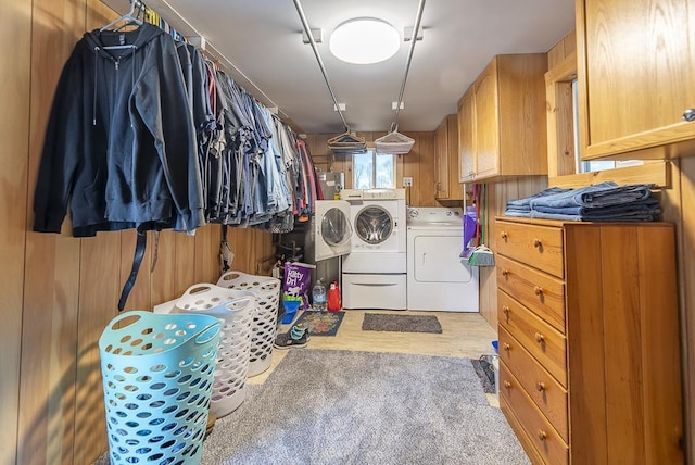 washroom with wooden walls, wood finished floors, cabinet space, and washer and dryer