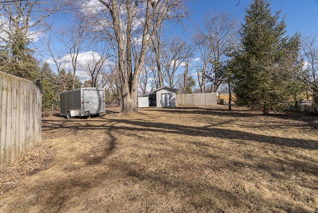 view of yard featuring an outbuilding, fence, and a shed