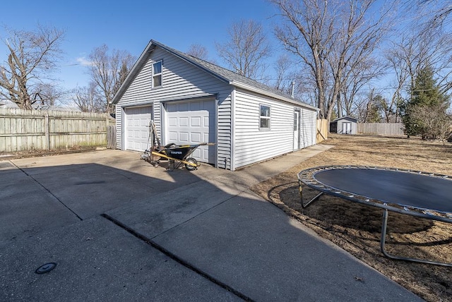 detached garage featuring a trampoline and fence