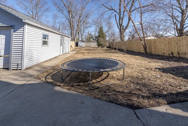 view of yard with a trampoline, fence, and an outdoor structure