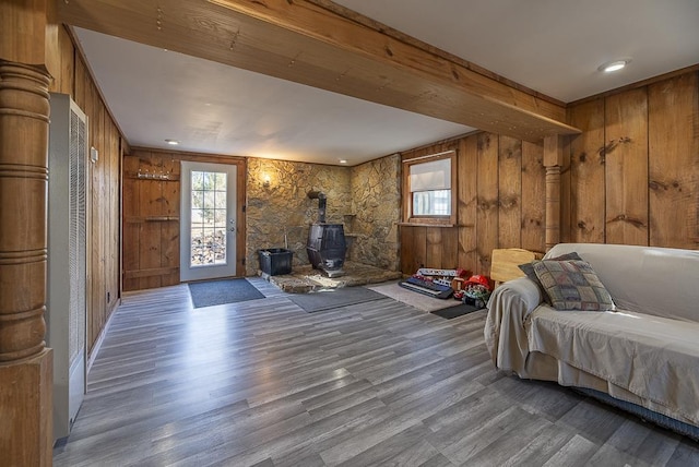 bedroom featuring a wood stove, wooden walls, and wood finished floors