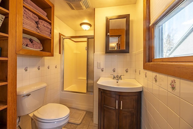 bathroom featuring toilet, vanity, visible vents, tile walls, and tile patterned floors