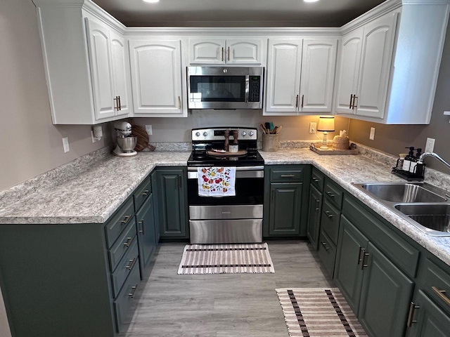 kitchen with sink, white cabinetry, appliances with stainless steel finishes, and light wood-type flooring